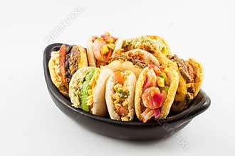 Arepas with assorted fillings served in a black ceramic dish