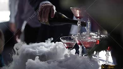 People pouring wine to pyramid of glasses with champagne