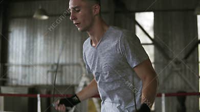 Short haired, caucasian man in white T shirt and red shirtsworking hard in boxing gym. Diligently exercising with
