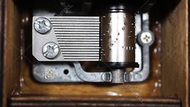 Macro of intricate music box mechanism and gears rotating as it plays and turns.