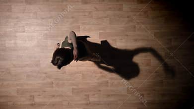 Silhouette of young elegant girl is dancing on wooden floor, ballet concept, movement concept, top shot