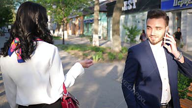 Love at first sight, elegant man talking on phone pays attention to passerby woman on open air
