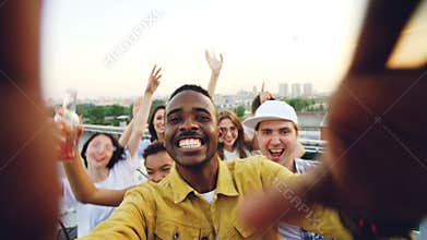 Point of view shot of handsome African American man partying with friends on rooftop, dancing and having fun with drinks