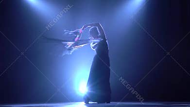 Dancing woman is with a manton in the hands of a Spanish incendiary dance. Llight from behind. Smoke background
