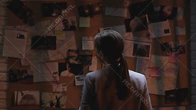 Lady private agent looking at crime investigation board, drinking cup of coffee