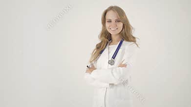Beautiful female doctor in white coat looking at camera and smiling while standing with crossed arms