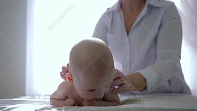 Child massage, woman in white lab coat massages back of a small boy on background of bright window