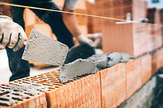 Construction worker details, protective gear and trowel with mortar building brick walls