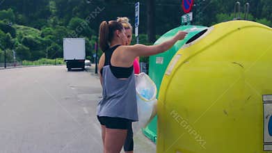 Girls throwing garbage to recycling dumpster