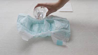 Girl pours water from a glass in a children`s diaper, close-up, diapers and water