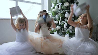 Holidays, small girls throw gift boxes into air and smily in chic dresses near xmas tree with white ornaments