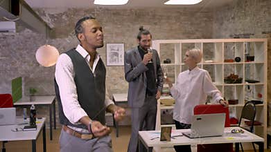 African businessman is dancing in office, colleaues are drinking champange and talking, relax concept, company party