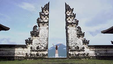 Woman raise hands standing in Pura Lempuyang, looking at Agung volcano.Indonesia