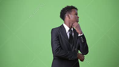 Young African businessman against green background