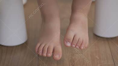 The legs of a little girl hang from the chair, not reaching the floor. A child is sitting on a chair