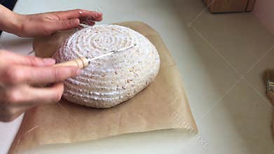 Woman scoring the dough with bread lame.