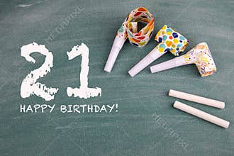 Celebrating 21 st years birthday. Birthdays and party whistles on a green board