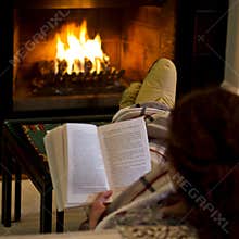 Woman reading by fireplace