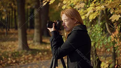 woman photographer photographing autumn landscape park with mirrorless camera