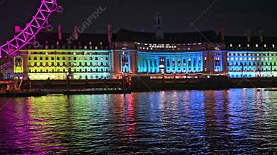 PANNING shot of Westminster Bridge to County Hall and the London Eye colourfully lit at night