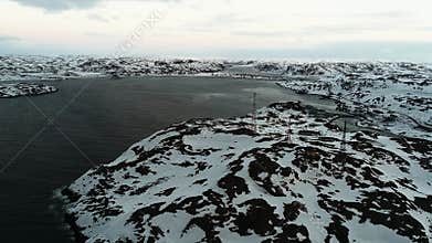 Drone flying over the shores of the Kola Peninsula in winter. Rocks covered with snow, cold waters of the Arctic Ocean