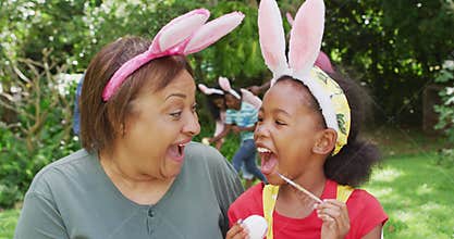 Animation of happy african american grandmother and granddaughter painting easter eggs in garden