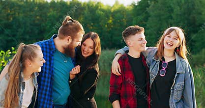 Teens multiethnic friends having fun near lake looking at camera enjoying their time