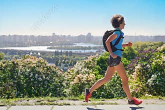 Active woman runner run commutes to work with backpack, city morning run commuting and healthy lifestyle concept, skyline of Kyiv