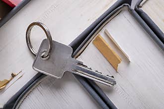 The key to the door in a single-family house laid on the spines of books. Metal key for patent lock