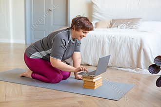 Photo of a senior woman looking for a Pilates workout tutorial online.