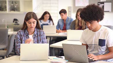 Multiethnic students studying on laptop in it classroom