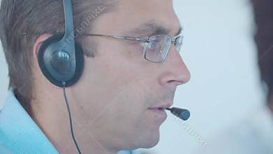 Focused male call center worker in headset taking call