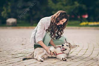 Photo of funky positive curly hair woman play with favorite pet dog wear striped shirt green jeans bag in park outdoors