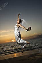 Bride jumping on beach.