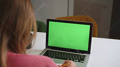 Green screen laptop computer concept: online distance education, video call conference. Over the shoulder woman student