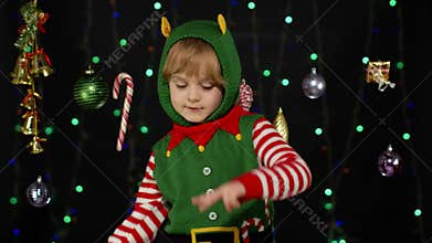 Kid girl in Christmas elf Santa helper costume dancing, fooling around. New Year holiday celebration