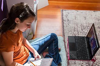 downward view of girl working on homework for school while homeschooling
