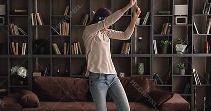 Energetic laughing young 30s woman dancing at home.