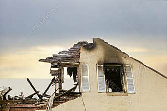 Close up of a roof top of a stucco home charred and burned.