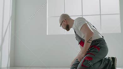 Bald builder writes on clipboard measuring parquet plank