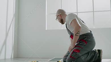 Handyman writes on clipboard and measures parquet board