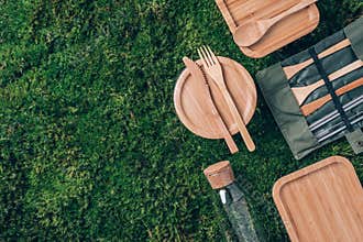 Eco friendly bamboo cutlery set, glass jars, bottle, straws, lunch boxes on green grass, moss background. Zero waste