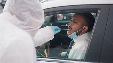 Drive through covid testing station. Doctor performing swab test on driver
