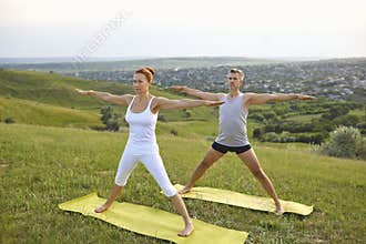 Middle aged couple doing Five Pointed Star asana while practicing yoga together on grassy hill