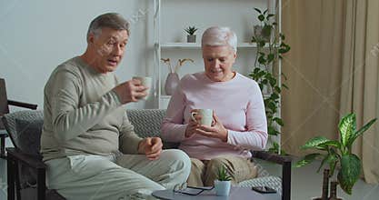 Old man brings his beloved wife cup of hot tea cappuccino coffee take care of female spouse. Affectionate mature granny