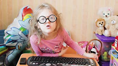 The little girl gets angry and bangs on the keyboard with her fist.