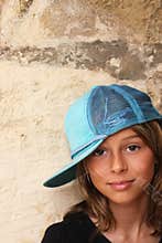 Young girl with hat with back against the wall