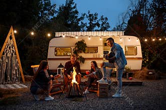 Friends warming themselves by the bonfire, camping