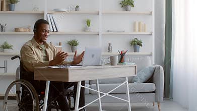 Disabled Black Man In Wheelchair Video Calling Using Laptop Indoors