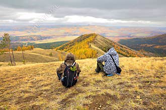 Two mature tourists at the top of the ridge admire the Ural mountains and taiga